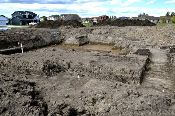 An excavation site holier a new housing development  shows the layout of a new home ready to have forms and a concrete foundation poured.