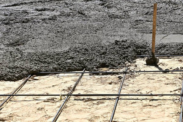 A post maul is located in the midst of a recently poured  wet concrete project.