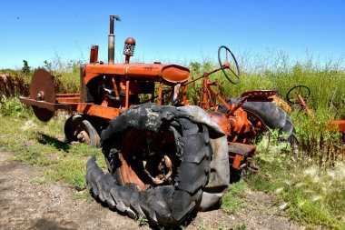 A shredded rotten tire in on an old tractor with a frontal circular saw blade. clipart