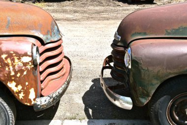 The front bumpers of two old rusted pickups are nearly touching. clipart