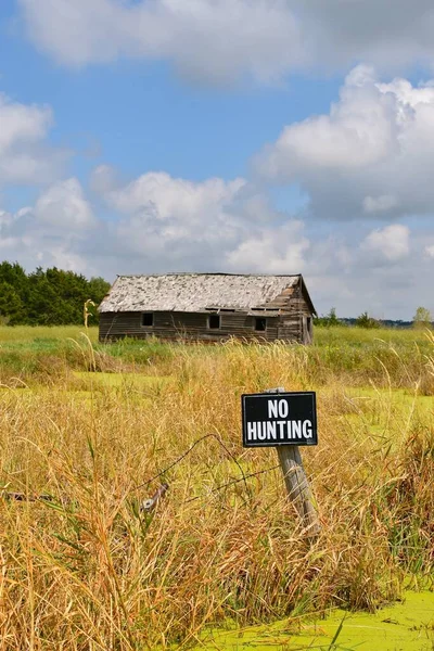 An old wood shed located a marshy setting is protected by a NO HUNTING sign.