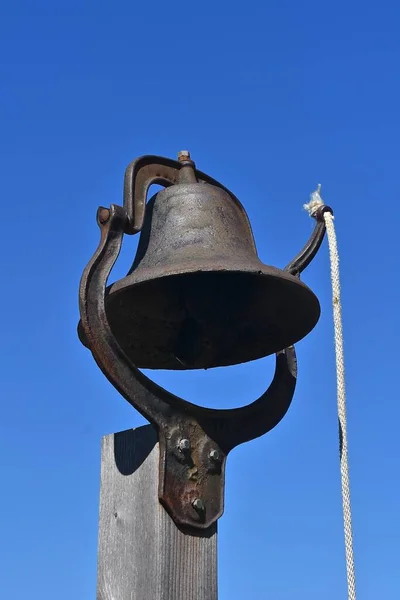 A cast iron bell with a pull rope is located used to call classes in  old one room schoolhouse