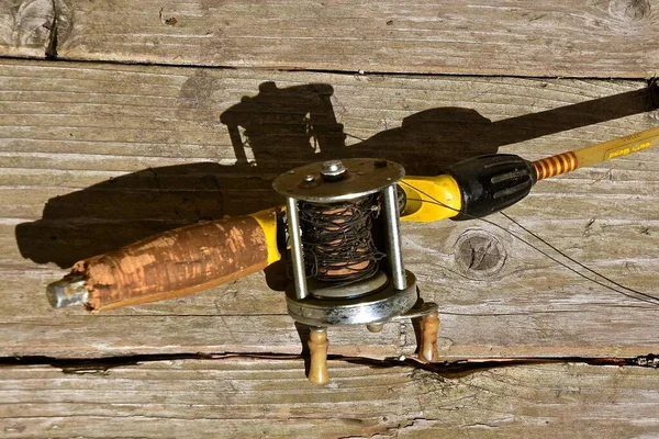 An old vintage fishing spinning rod and reel displays a worn-out
