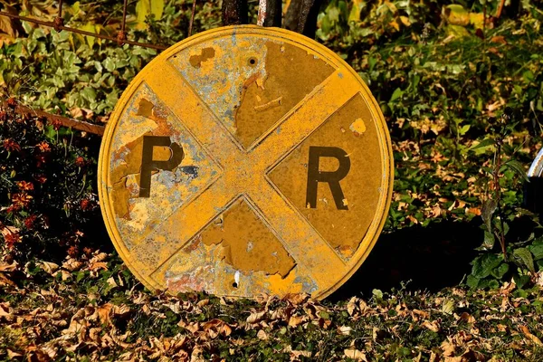 A circular railroad sign with and R and R, but part of the first R is missing.