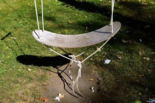 A curved board hanging by ropes  is used as the base of a swing