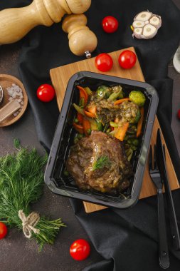 Ahşap tahta üzerinde siyah tepsisinde sebzeli haşlanmış et
