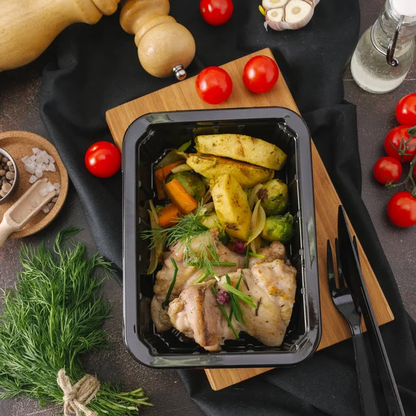 Grilled chicken fillet with vegetables in black tray on wooden board