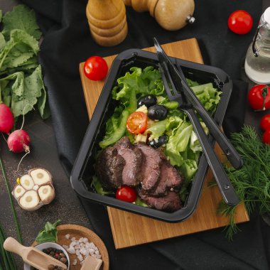 Et dilimleri sebze ile siyah tepsi içinde fırında