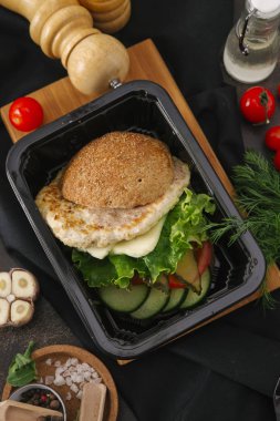 Portre siyah tepsisinde tavuk pirzola, marul ve sebze salatası ile Burger