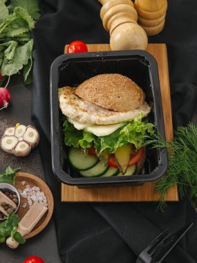 Portre siyah tepsisinde tavuk pirzola, marul ve sebze salatası ile Burger