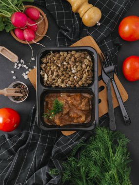 Çatal ve bıçak ahşap tahta üzerinde siyah tepsisinde pişirilmiş Etli Nohut