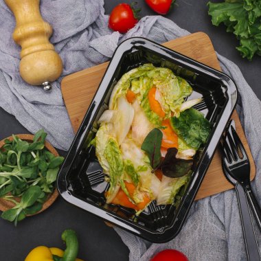 Bıçak ve çatal ile siyah tepsisinde sebze salatası marul, biber ve pancar yaprakları