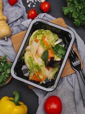 Bıçak ve çatal ile siyah tepsisinde sebze salatası marul, biber ve pancar yaprakları