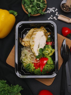 Tavuk, brokoli, kırmızı biber ve siyah tepsisinde erişte ile sağlıklı yemek