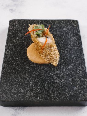 Gurme yemek sarılı balık, susam ve tropikal sos ile siyah taş tabakta