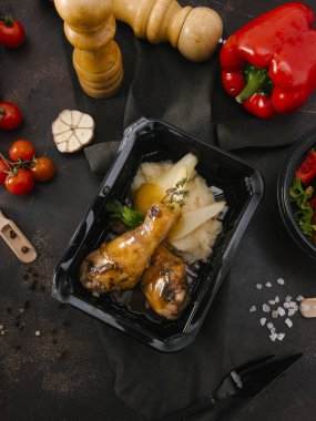 Fırında tavuk budu karanlık tablo üzerinde siyah tepsisinde peçete ile hizmet patates püresi ile üstten görünüm