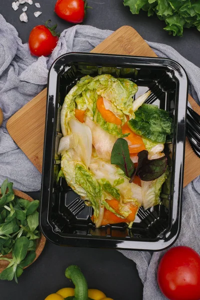 Bıçak ve çatal ile siyah tepsisinde sebze salatası marul, biber ve pancar yaprakları