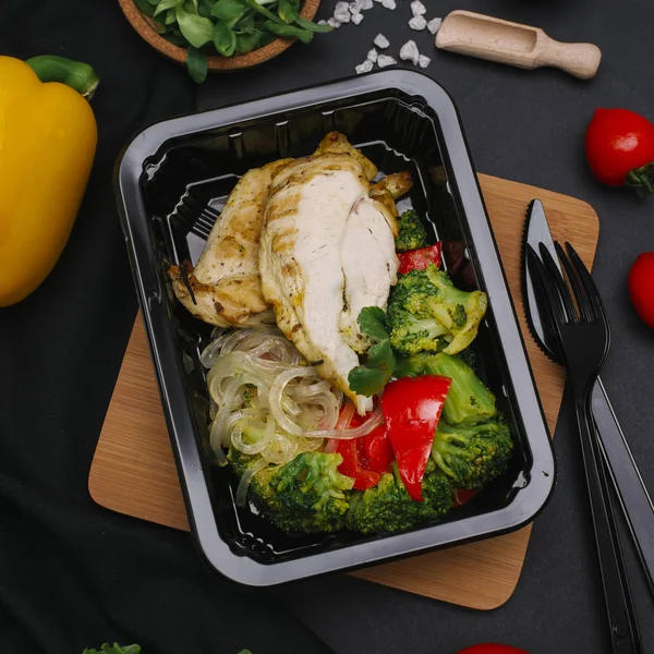 Tavuk, brokoli, kırmızı biber ve siyah tepsisinde erişte ile sağlıklı yemek