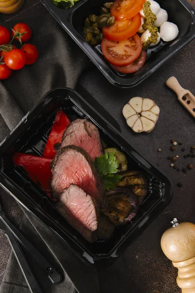 Bıçak ve çatal ile sığır eti dilimleri ile siyah kasetlerine Caprese salatası kavrulmuş