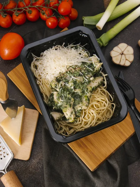 Top view of pasta with fish and parmesan in black tray