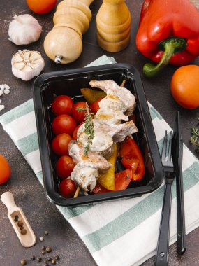 Somon ızgara domates ve biber bıçak ve çatal ile siyah tepsisinde