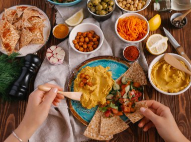 Üstten görünüm eller ve humus sebze ve Pide ile servis 