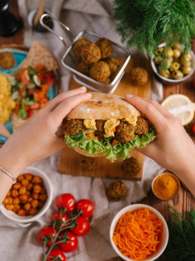 Burger falafel topları, humus ve sebze tutan kadın