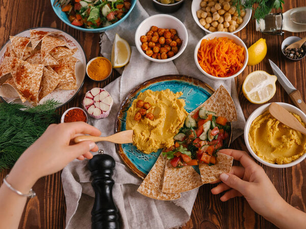 Top view of female hands and hummus served with vegetables and pita 