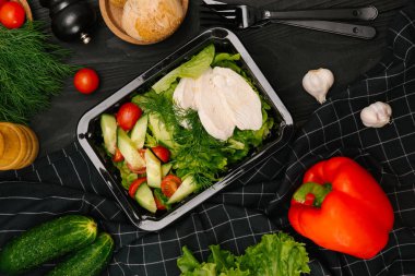 Haşlanmış tavuk göğsü plastik kap içinde yeşil sebze salatası ile servis