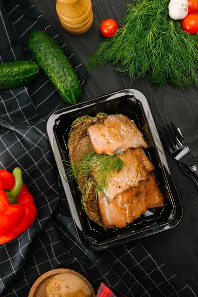 Roasted salmon fillet with corn cakes in plastic box