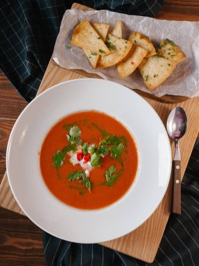 Ahşap tahta üzerinde mısır cipsi ile servis domates çorbası krem