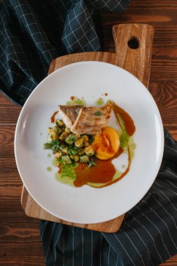 Kızarmış balık parçaları ile squash ve soslar ahşap tahta üzerinde beyaz tabakta servis