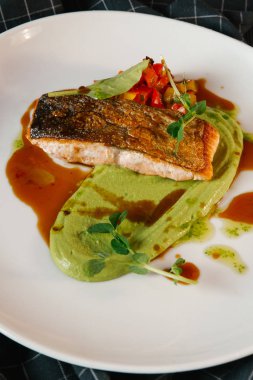 Kavrulmuş balık sebze ve beyaz plaka üzerinde avokado sosu ile servis