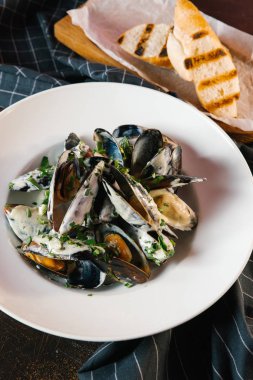 Buğulanmış midye tost ile beyaz tabakta 
