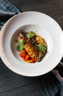 Kızarmış balık sosu ve beyaz tabakta sebze güveç ile servis