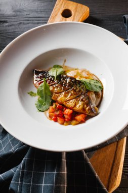 Kızarmış balık sosu ve beyaz tabakta sebze güveç ile servis