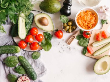 Beyaz beton zemin üzerinde sebze salatası için malzemelerin üstten görünüm 