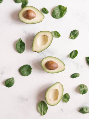 Fesleğen ile kesilerek olgun avokado satırında beyaz beton zemin üzerine bırakır