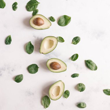 Fesleğen ile kesilerek olgun avokado satırında beyaz beton zemin üzerine bırakır