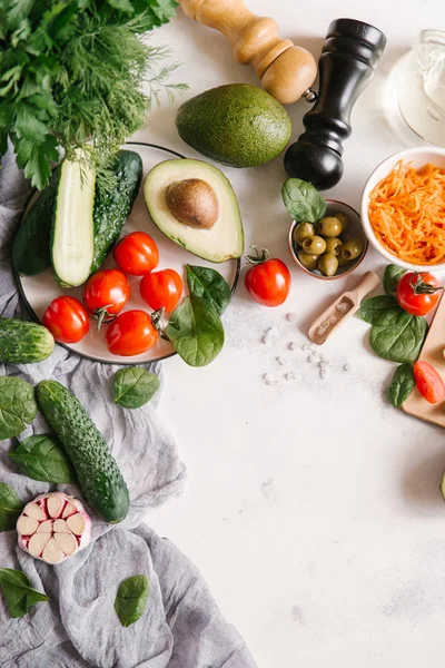 Beyaz beton zemin üzerinde sebze salatası için malzemelerin üstten görünüm 