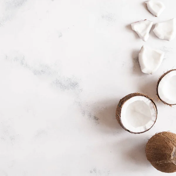 Top view of broken coconut pieces on white stone background