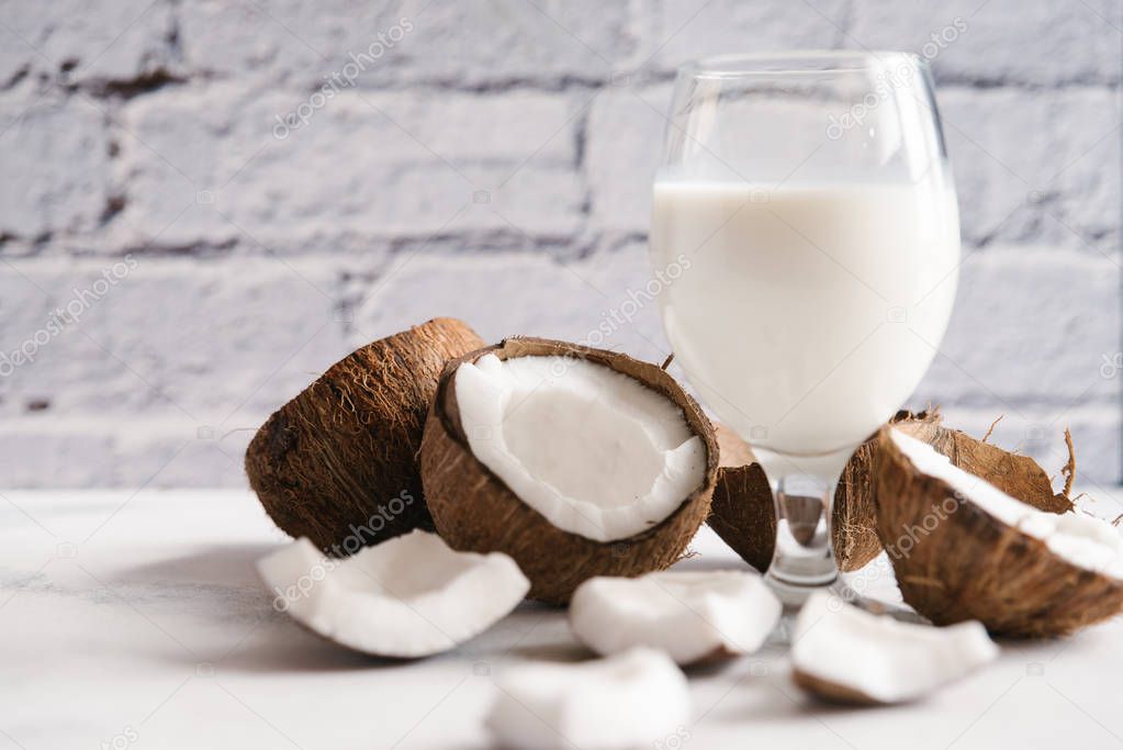 Coconut milk with broken coconut on white table
