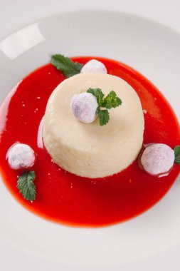 Çilek sos ile beyaz sufle ve beyaz tabak içinde nane yaprakları