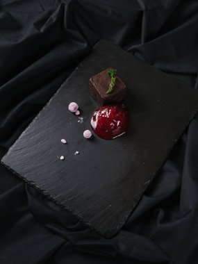 Siyah taş gemide frambuaz sos ile servis çikolatalı browni kek 