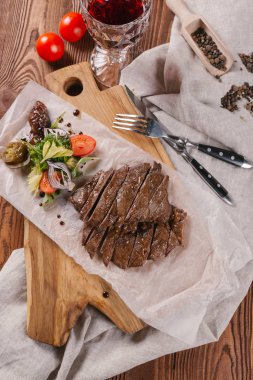 Yeşil salata ve bir bardak kırmızı şarap ile kıyılmış sığır eti biftek servis