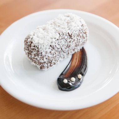 Hindistan cevizi gevreği beyaz plaka üzerinde çikolata soslu çikolatalı kek