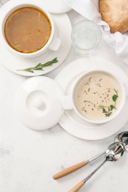 Beyaz arka plan üzerinde otlar ile iki tür krem çorba servis