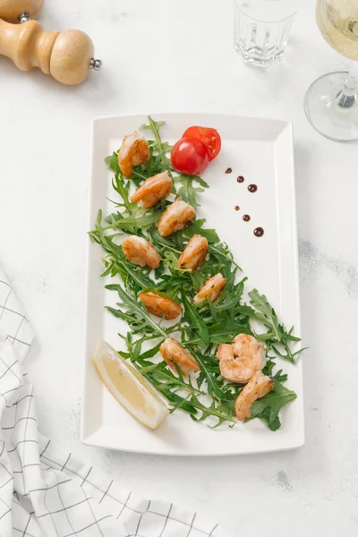 Izgara karides roka, limon dilimi ve beyaz tabakta domates ile servis