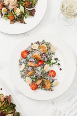 Yeşil salata domates, bıldırcın yumurtası ve beyaz plaka üzerinde Kızarmış karides ile