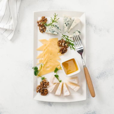 Peynir tabağı ile fındık ve bal beyaz masada